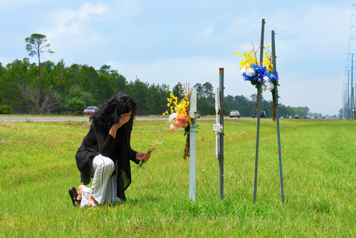 Image of a busy intersection showing the aftermath of a fatal car accident with a car accident lawyer discussing a wrongful death claim with family members.