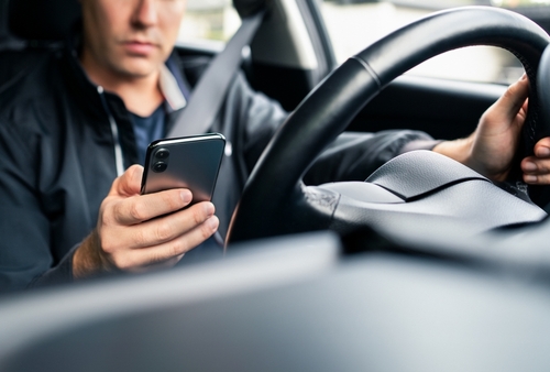 Fort Mill rideshare accident lawyer – distracted driver checking phone for rideshare rides before a potential car accident.