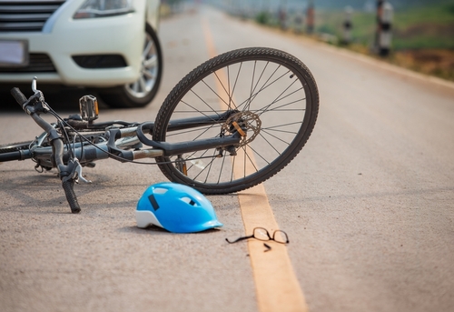 Damaged bicycle and fallen glasses on the road after a collision with a car, illustrating cases handled by a bicycle accident lawyer.
