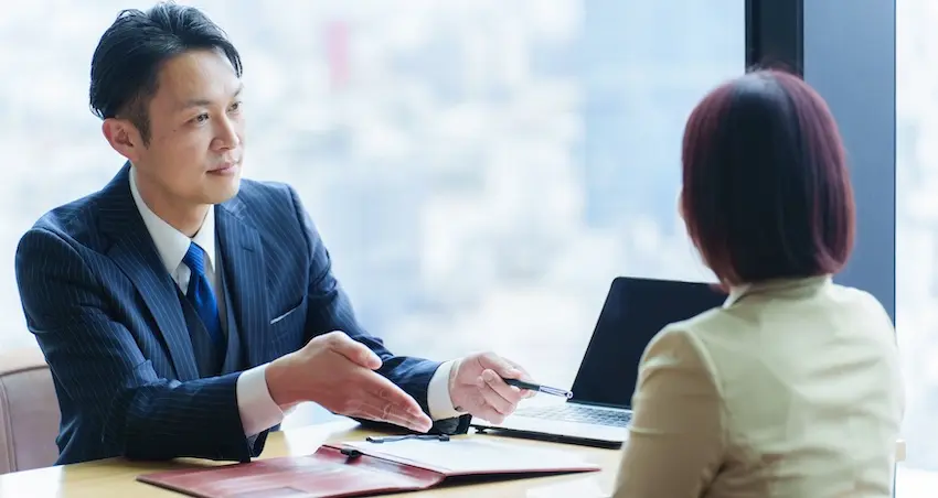 An auto accident lawyer is consulting with a female client about an injury claim and legal options during an office meeting.