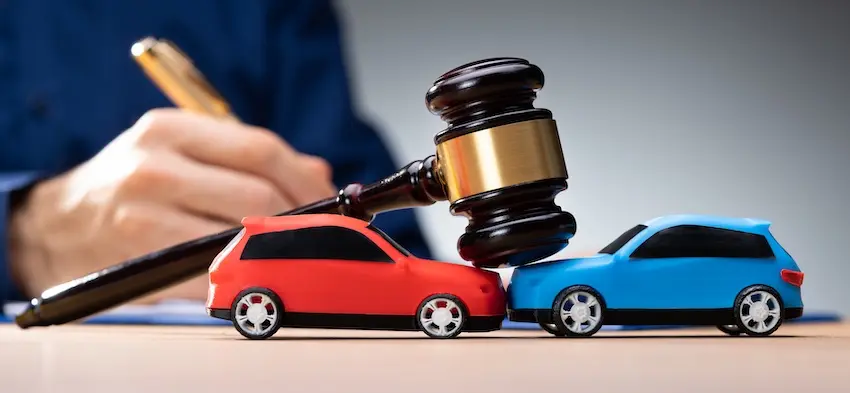 Car crash claims legal process represented by a gavel and toy vehicles symbolizing litigation.