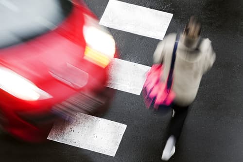 Car in a crosswalk near a woman who will need a pedestrian accident attorney