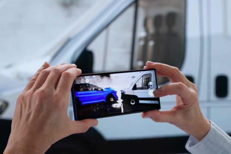A person holds a smartphone displaying a blue car colliding with a white van in front of an actual white van representing the importance of documenting and reconstructing evidence for car accident claims in Spartanburg SC.