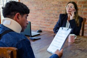 A injured client with a neck brace is reviewing legal documents with ab attorney during a car accident consultation meeting at Panchenko Law Firm in Charlotte.