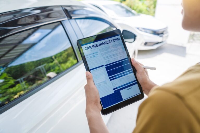 A person in a yellow shirt holds a tablet displaying a digital car insurance form with a stylus in hand while standing beside a white vehicle depicting the modern process of completing car accident insurance documentation at the scene or point of purchase in Charlotte NC.
