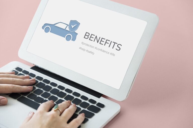 A woman's hands type on a dark laptop keyboard while the screen displays a graphic of a car with a shield and checkmark alongside the word "Benefits" and hashtags reading protection- confidence- help- and safety- illustrating an accident victim researching the full scope of compensation benefits available to them following a car crash and could use help from Panchenko Law Firm.