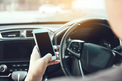 A rideshare driver on their phone while driving showing how a rideshare accident can happen and the need for a rideshare accident lawyer.