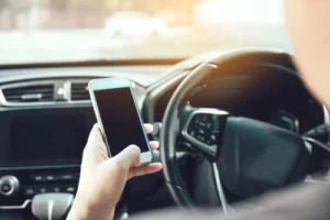 A rideshare driver on their phone while driving showing how a rideshare accident can happen and the need for a rideshare accident lawyer.