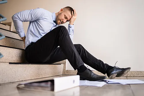 Man holding back and head in pain after falling down stairs